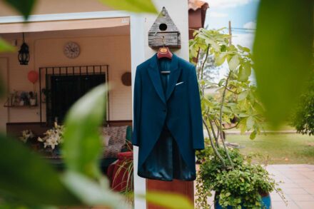 El chaqué azul del novio cuelga de una casita de pájaros de madera en el porche