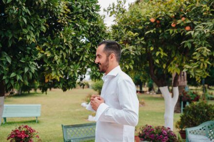 El novio se abrocha el puño de la camisa entre naranjos, en los preparativos de su boda en Hacienda Los Molinillos (Sevilla)