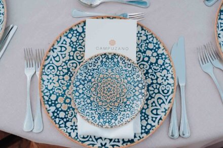 Un servicio de mesa visto desde arriba, con platos de cerámica de dibujo azul y la minuta sobre la servilleta