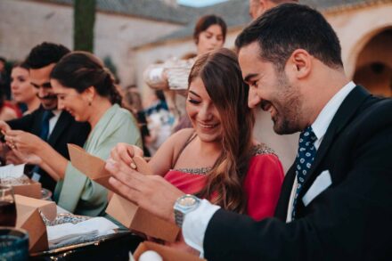 Invitados abren entre risas unas cajitas de cartón en la mesa del banquete