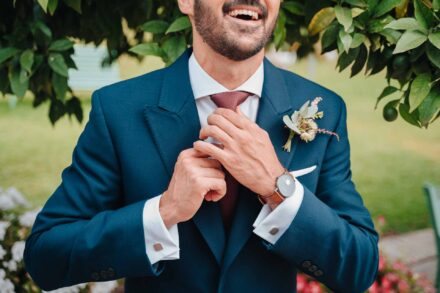 El novio, ya con el chaqué y una flor en la solapa, se ajusta la corbata y se ríe