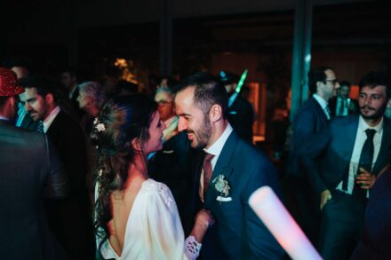 Los novios bailan cara a cara y se ríen en la pista, con la espalda abierta del vestido a la vista
