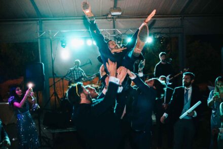 Los invitados mantean al novio por el aire delante del escenario donde toca el grupo