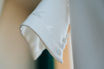 Close-up of the wedding dress cuff, with embroidered birds and fabric-covered buttons