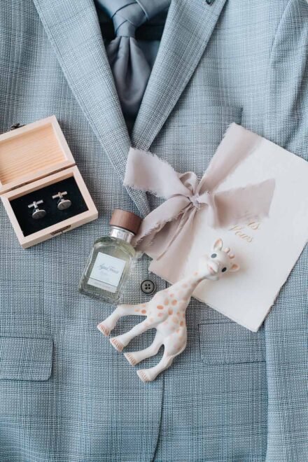 The groom’s checked jacket with cufflinks, cologne, a ribboned vows booklet and a toy giraffe