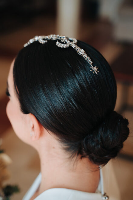 The bride from behind, showing her low bun and the jewelled headpiece running across her hair