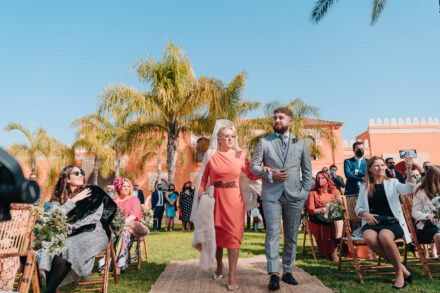The groom walks to the ceremony arm in arm with a woman in a white mantilla, in front of Hacienda Al-Baraka (Seville)