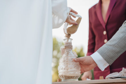 The bride pours sand into a cut-glass bottle held by the groom during the sand ceremony