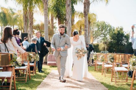 The couple walk arm in arm down the esparto aisle as guests throw rice over them