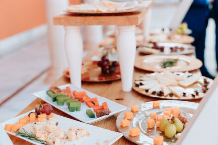 Plates of diced cheese, grapes and cheese wedges on a wooden table at the cocktail hour