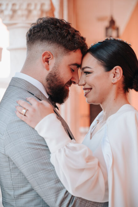 Close-up of the couple touching foreheads, him with eyes closed and her smiling with a hand on his shoulder