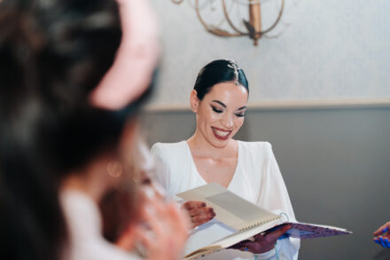 The bride smiles as she leafs through an open notebook held in her hands