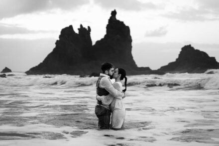 Los novios, empapados, se besan abrazados en el agua poco profunda, en blanco y negro