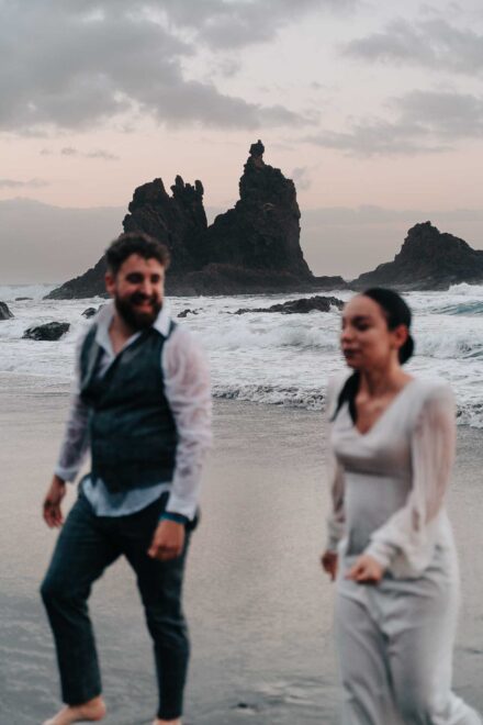 Los novios salen del mar empapados, él sonriendo, desenfocados ante las rocas y el cielo rosado