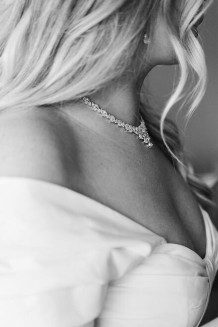 Detalle de la nuca y la espalda de la novia con un collar de brillantes, en blanco y negro