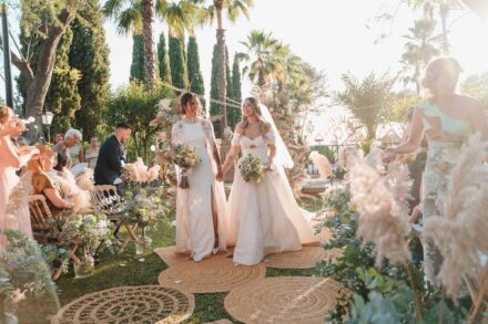 Las novias salen de la mano por el pasillo de alfombras de esparto entre los invitados de la ceremonia