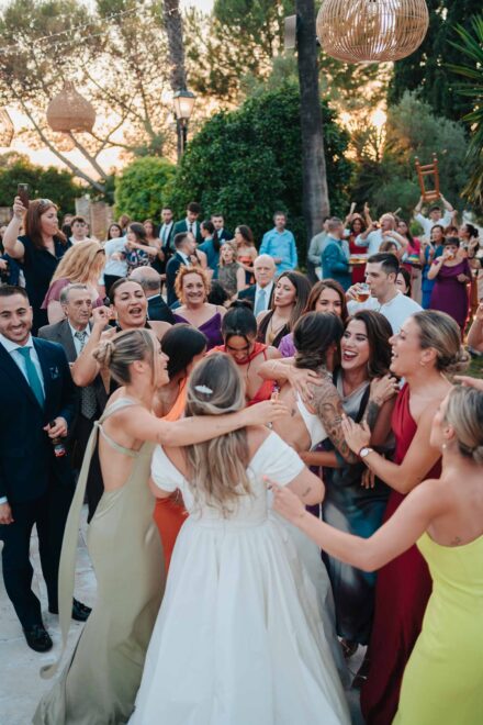 Un corro de invitadas abraza entre gritos y risas a una de las novias, de espaldas