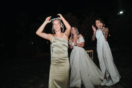 Andrea Medina baila con unas gafas sobre la cabeza mientras las novias aplauden detrás