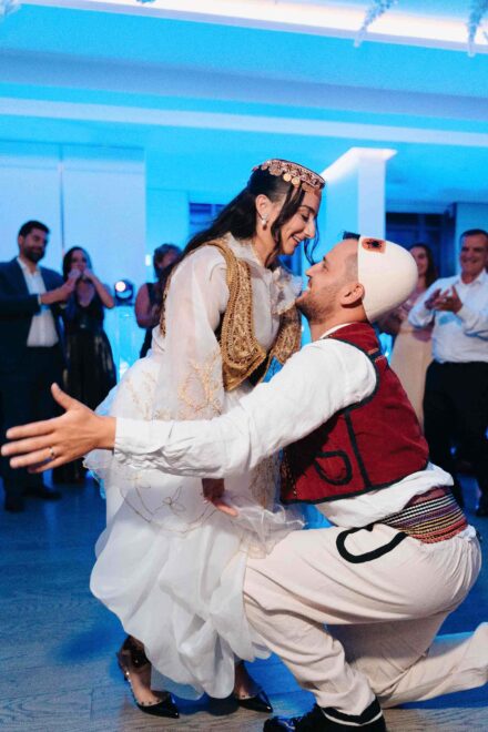Los novios, con trajes tradicionales bordados en oro y rojo, bailan frente a frente mientras los invitados aplauden