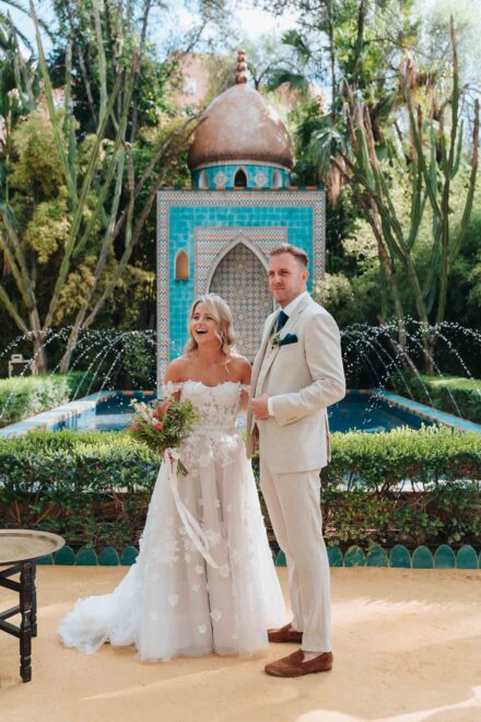 bride and groom standing in front of turquoise fountain during ceremony in seville