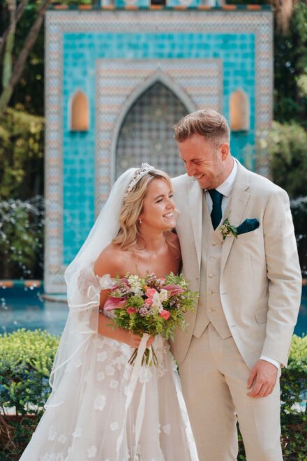 bride and groom standing in front of turquoise fountain during ceremony in seville