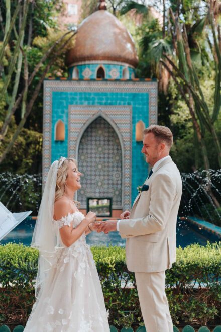bride and groom standing in front of turquoise fountain during ceremony in seville