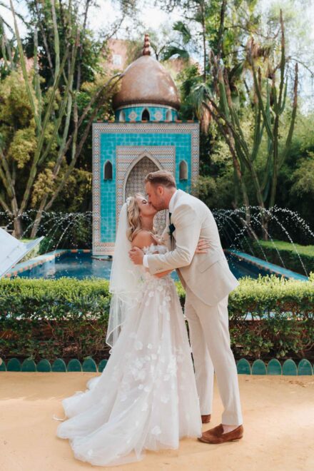 bride and groom standing in front of turquoise fountain during ceremony in seville