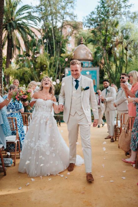 bride and groom walking down the aisle with guests cheering in hacienda villa luisa seville