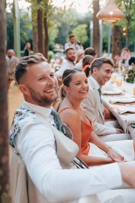 guests laughing around decorated table during outdoor wedding dinner in Seville