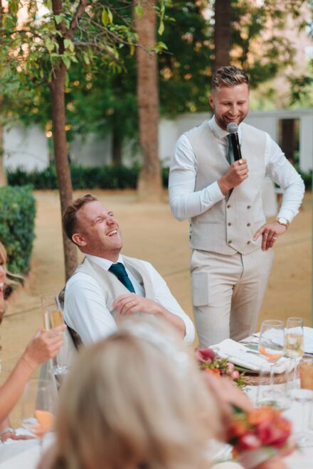 group of wedding guests smiling at camera seated at outdoor dinner table in Seville