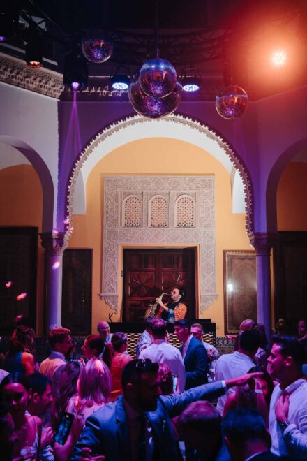 wedding guests dancing with live saxophonist under disco balls at Hacienda Villa Luisa Seville