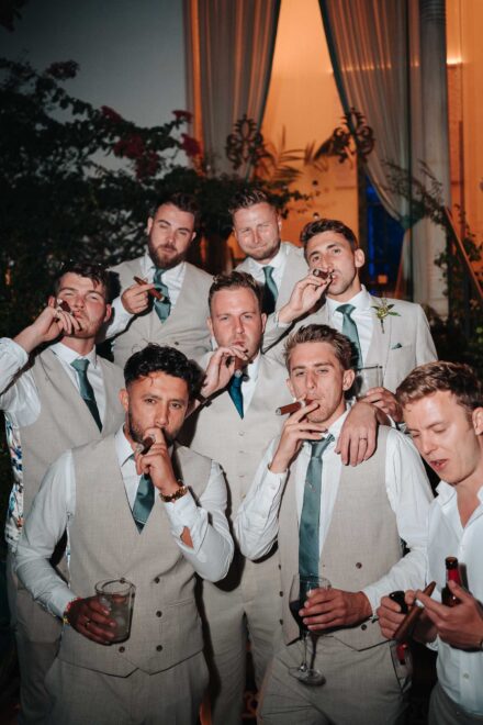 groom and groomsmen in beige suits smoking cigars during wedding party in Seville