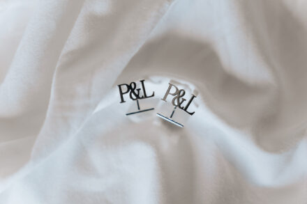 Close-up of personalized wedding cufflinks with the initials P&L on a white shirt during groom preparations