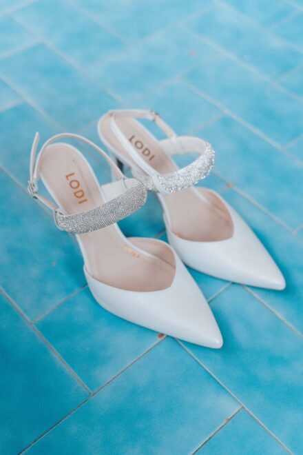 White bridal shoes on blue tiles during wedding preparations.