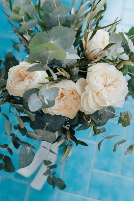 Bridal bouquet with cream roses and eucalyptus leaves on blue tiles during wedding preparations