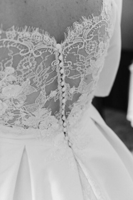 Black and white close-up of lace details on a bride’s wedding dress