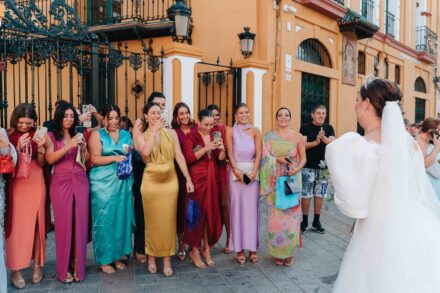Bride arriving in a vintage convertible car outside a church in Seville with guests watching