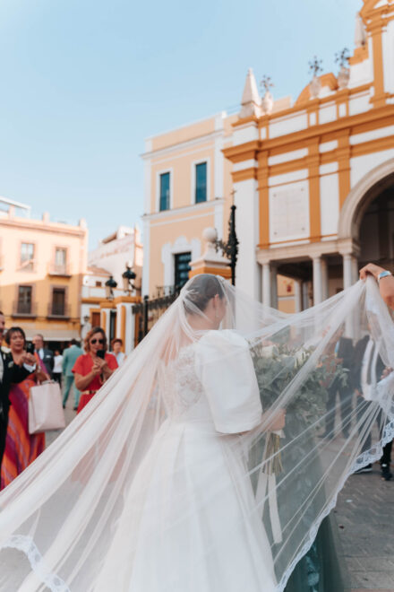 Bride arriving in a vintage convertible car outside a church in Seville with guests watching