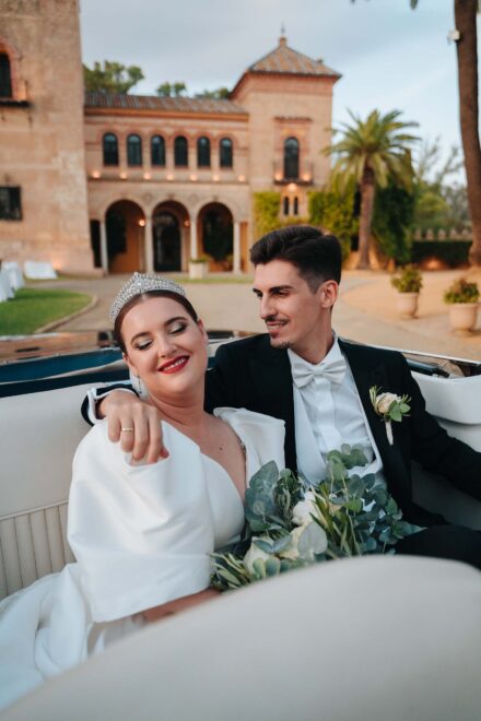 Bride and groom sitting in a vintage convertible at Castillo de la Monclova in Seville