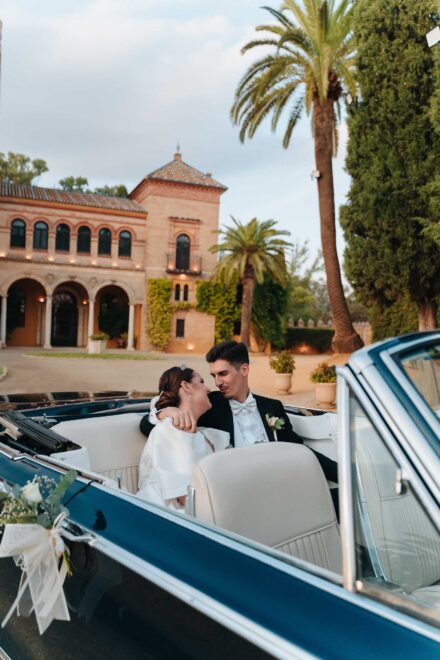 Bride and groom sitting in a vintage convertible at Castillo de la Monclova in Seville