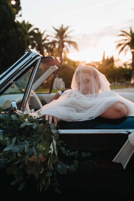 Bride smiling in a vintage convertible at sunset during a wedding at Castillo de la Monclova in Seville