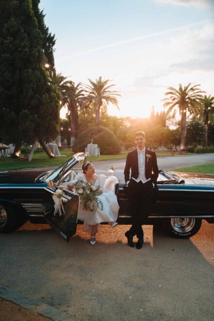 Bride and groom with a vintage convertible at sunset at Castillo de la Monclova in Seville