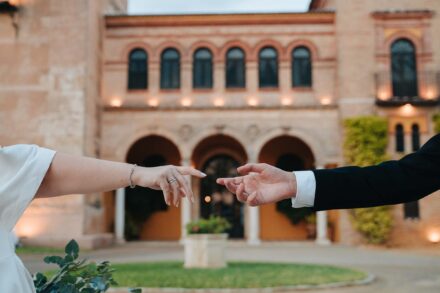 Bride and groom reaching for each other’s hands at Castillo de la Monclova in Seville
