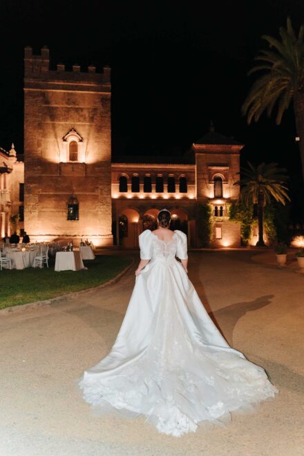 Bride walking at night in front of Castillo de la Monclova during a wedding reception in Seville