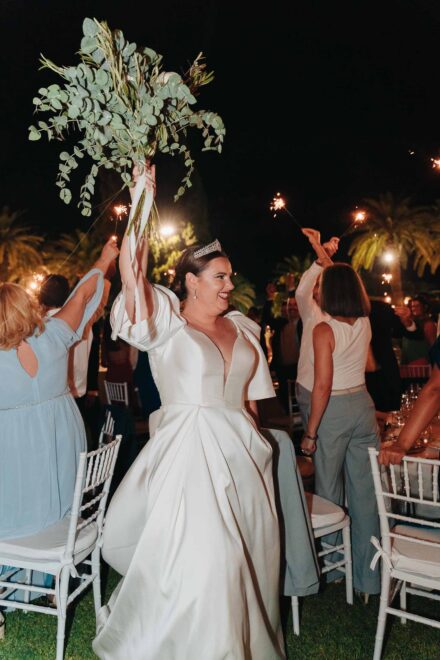 Bride celebrating with bouquet and sparklers during a night wedding reception in Seville