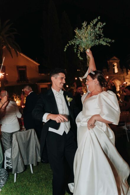 Bride and groom dancing with bouquet during night wedding celebration in Seville