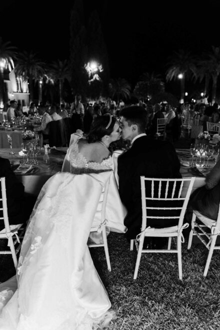 Bride and groom kissing during outdoor wedding dinner at night in Seville