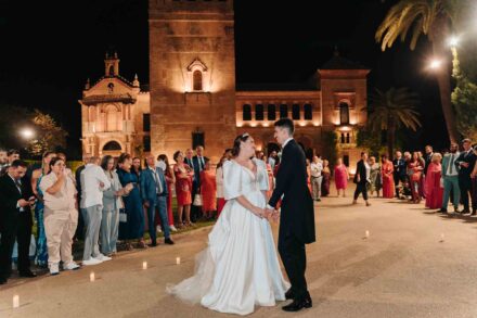 Bride and groom dancing surrounded by guests at night at Castillo de la Monclova in Seville.