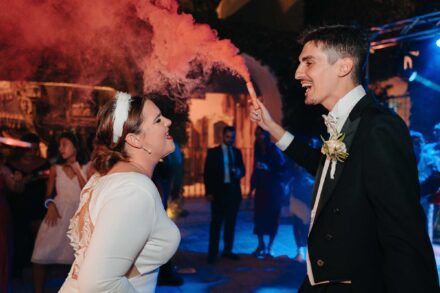 Bride and groom dancing with smoke flare during wedding party at Castillo de la Monclova in Seville