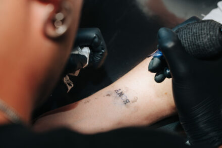 Tattoo artist tattooing the word “AMOR” on a guest’s arm during a wedding celebration